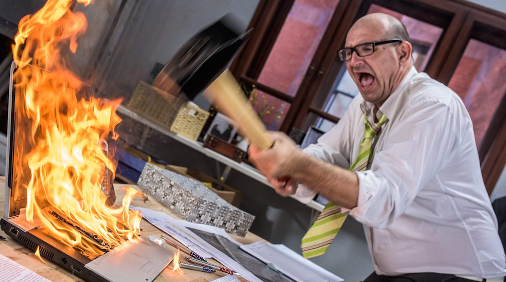 HR Manager hitting laptop on fire with hammer.